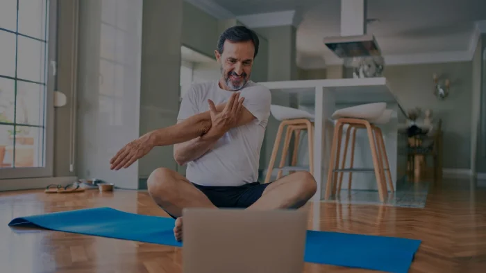 Homme senior en tailleurs au sol entrain de s'étirer les bras devant son ordinateur