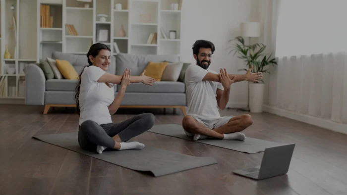 Adultes en tailleurs au sol entrain de s'étirer les bras devant un ordinateur