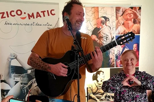 Chanteur et guitariste entrain de faire une représentation à un public handicapé
