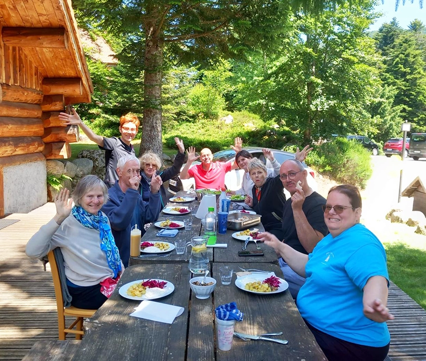 groupe de personnes joyeuses assis à une table de pique-nique entrain de déjeuner 