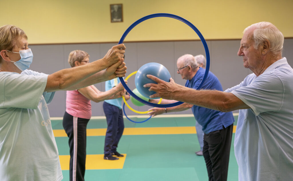 Cours de gym senior entrain de faire des exercices de cerceaux à deux