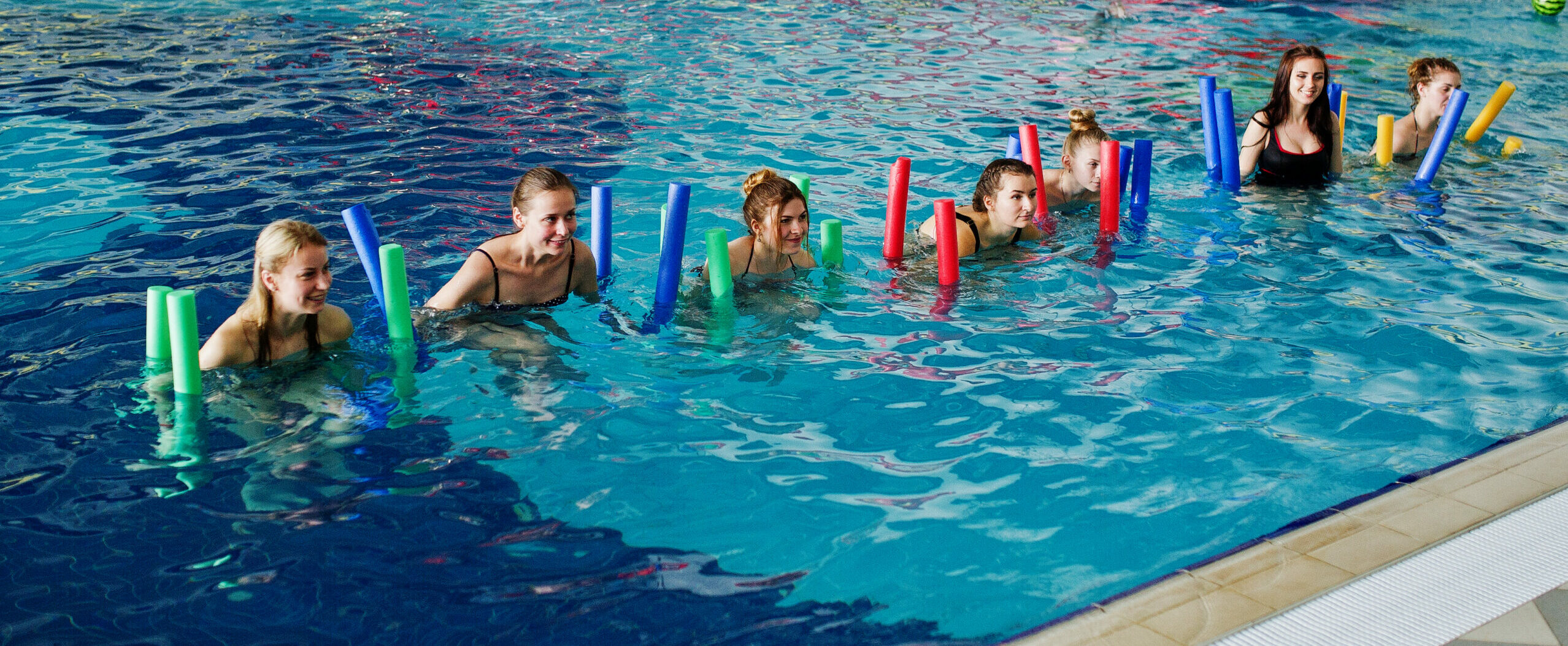 Groupe de jeune entrain de faire de l'aquagym avec des frites en mousse