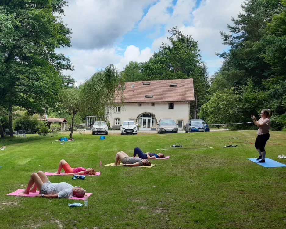 Groupe d'adultes en séance de yoga dans l'herbe