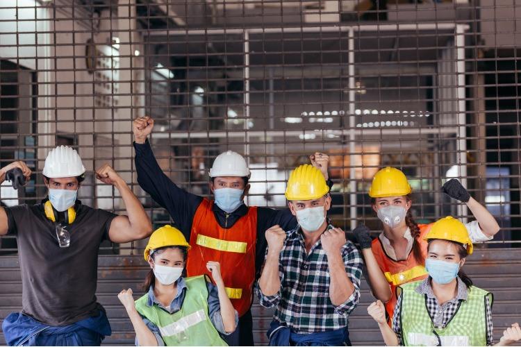 Salariés avec des casques montrant leurs muscles